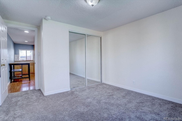 unfurnished bedroom with carpet flooring, a closet, and a textured ceiling