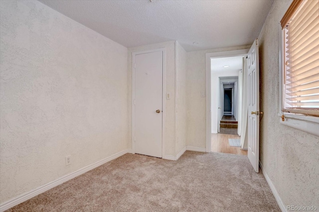 carpeted spare room featuring a textured ceiling and a wealth of natural light