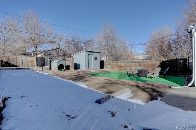 yard covered in snow with a patio area and a storage shed