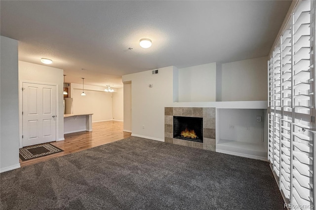 804 Summer Hawk Dr Unit 5105, Longmont, CO 80504 - unfurnished living room featuring carpet, a tiled fireplace, a textured ceiling, and baseboards