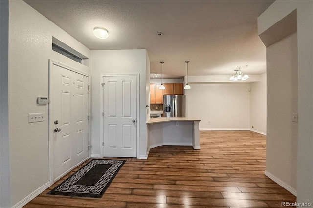 804 Summer Hawk Dr Unit 5105, Longmont, CO 80504 - kitchen with stainless steel fridge with ice dispenser, a peninsula, wood-type flooring, a kitchen breakfast bar, and a chandelier