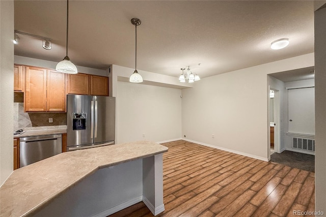 804 Summer Hawk Dr Unit 5105, Longmont, CO 80504 - kitchen featuring appliances with stainless steel finishes, dark wood finished floors, backsplash, light countertops, and hanging light fixtures