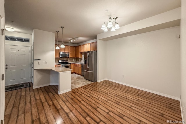 804 Summer Hawk Dr Unit 5105, Longmont, CO 80504 - kitchen with appliances with stainless steel finishes, decorative backsplash, wood finished floors, a peninsula, and light countertops