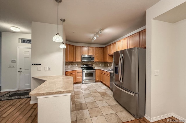 804 Summer Hawk Dr Unit 5105, Longmont, CO 80504 - kitchen featuring stainless steel appliances, a peninsula, light countertops, tasteful backsplash, and pendant lighting