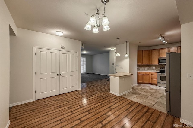 804 Summer Hawk Dr Unit 5105, Longmont, CO 80504 - kitchen with appliances with stainless steel finishes, open floor plan, light wood finished floors, tasteful backsplash, and a chandelier