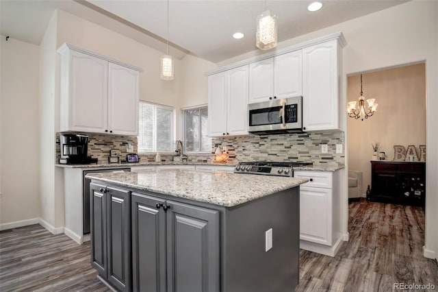 16084 Stonebriar Dr, Parker, CO 80134 - kitchen with appliances with stainless steel finishes, white cabinetry, a sink, wood finished floors, and recessed lighting