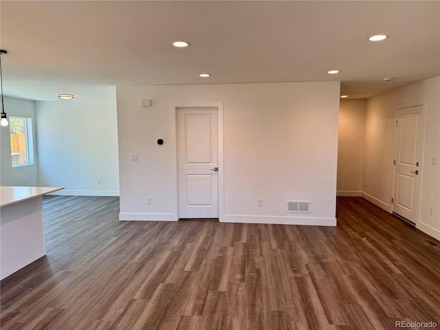 empty room featuring dark wood finished floors, recessed lighting, visible vents, and baseboards