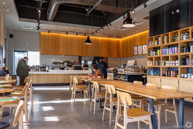 kitchen featuring visible vents, a high ceiling, finished concrete floors, and brown cabinetry