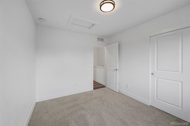 unfurnished bedroom featuring carpet flooring, baseboards, visible vents, and attic access