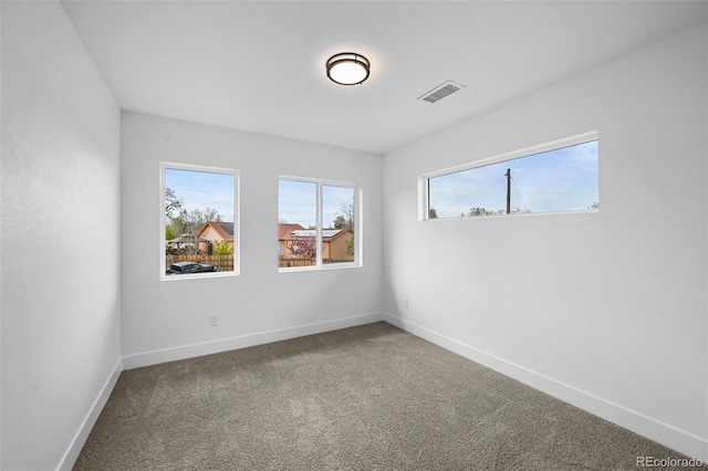 spare room with baseboards, a wealth of natural light, visible vents, and carpet floors