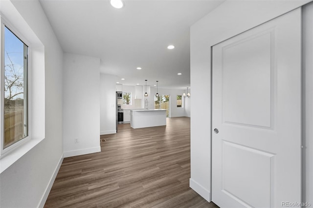 unfurnished living room featuring baseboards, dark wood finished floors, and recessed lighting