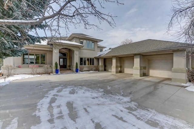 prairie-style home with a garage, concrete driveway, and stucco siding