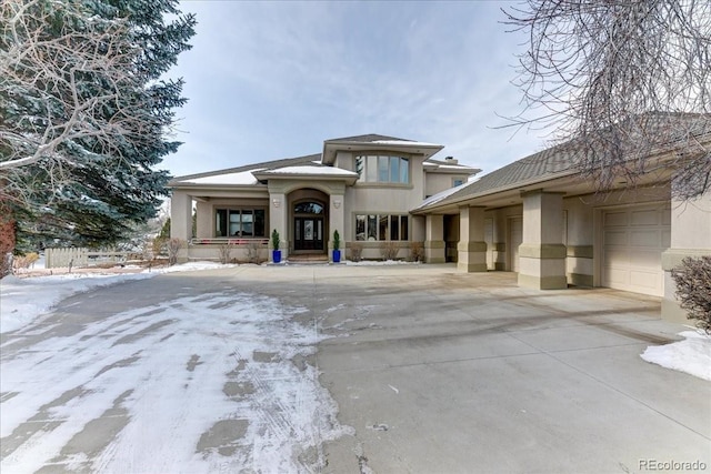 prairie-style home featuring concrete driveway, an attached garage, and stucco siding