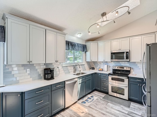 13358 Briarwood Dr, Broomfield, CO 80020 - kitchen with appliances with stainless steel finishes, a sink, lofted ceiling, backsplash, and light wood-style flooring