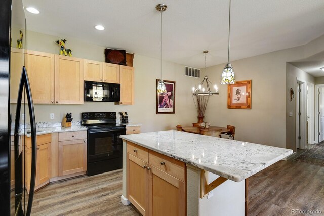 kitchen featuring light brown cabinetry, black appliances, wood-type flooring, hanging light fixtures, and a breakfast bar area