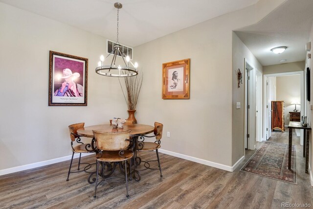 dining area featuring dark wood-type flooring and an inviting chandelier