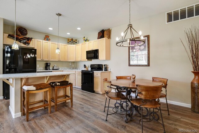 kitchen with a center island, black appliances, hardwood / wood-style flooring, and hanging light fixtures