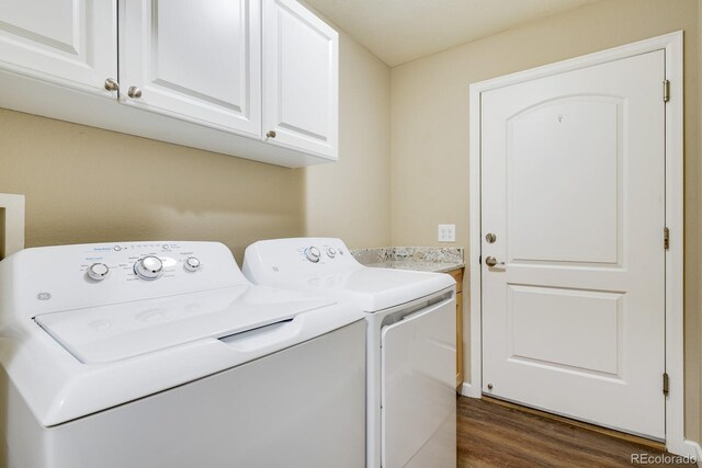 laundry area with cabinets, dark hardwood / wood-style floors, and washing machine and clothes dryer