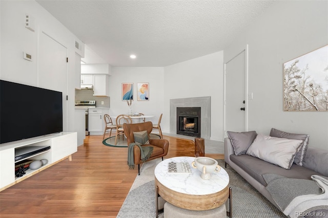 living area with a textured ceiling, a fireplace, and light wood-style floors