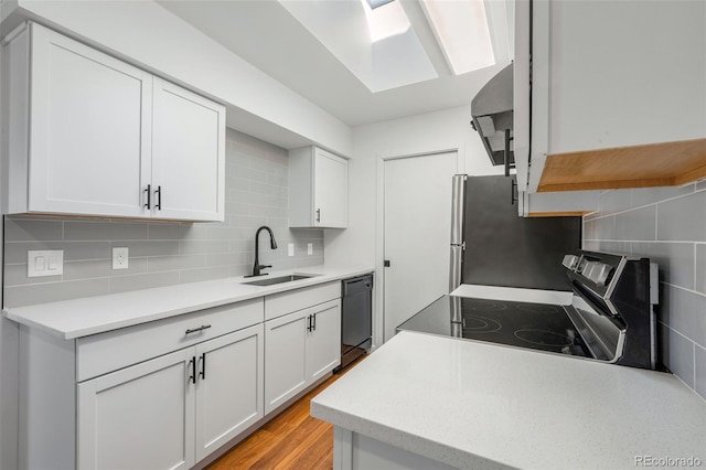 kitchen with decorative backsplash, stainless steel appliances, light countertops, white cabinetry, and a sink