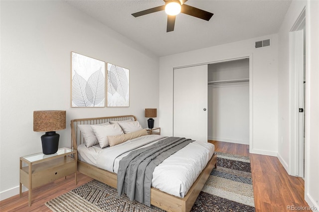 bedroom with baseboards, a closet, visible vents, and wood finished floors