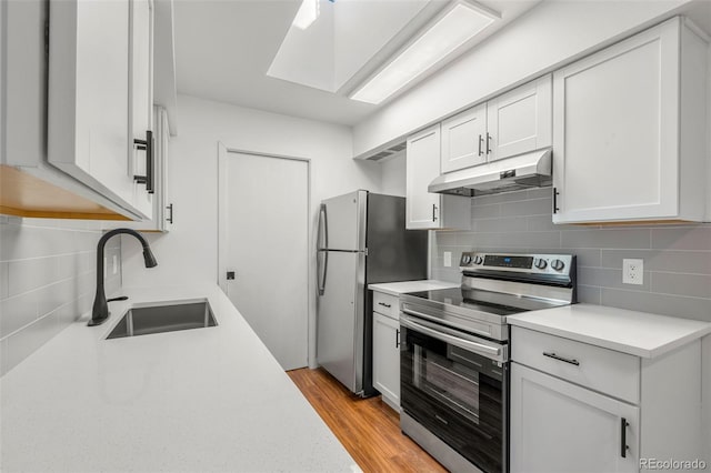 kitchen featuring decorative backsplash, appliances with stainless steel finishes, light countertops, under cabinet range hood, and a sink