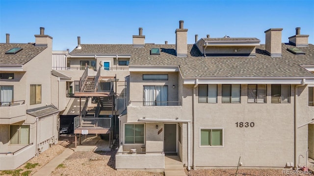 back of house featuring roof with shingles, a patio, a balcony, and stucco siding