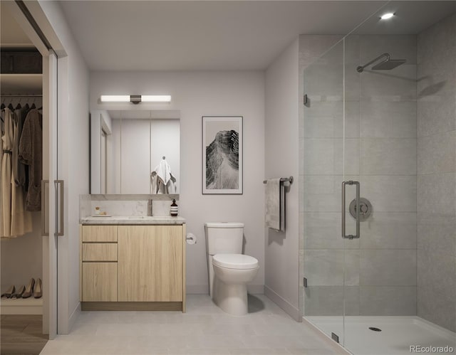 bathroom featuring baseboards, toilet, a walk in closet, vanity, and a shower stall