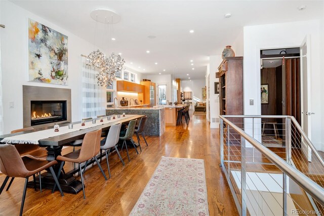 dining room featuring light wood finished floors, a glass covered fireplace, and recessed lighting