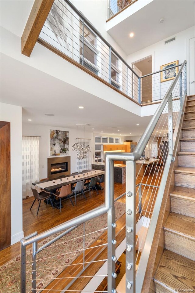 staircase with a towering ceiling, a glass covered fireplace, and recessed lighting