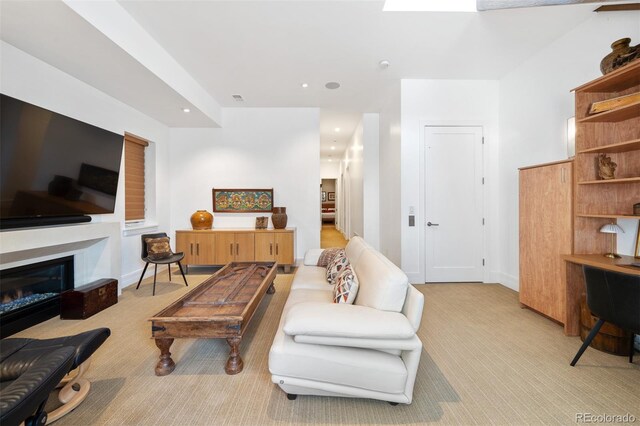 living room featuring light carpet, baseboards, recessed lighting, and a glass covered fireplace