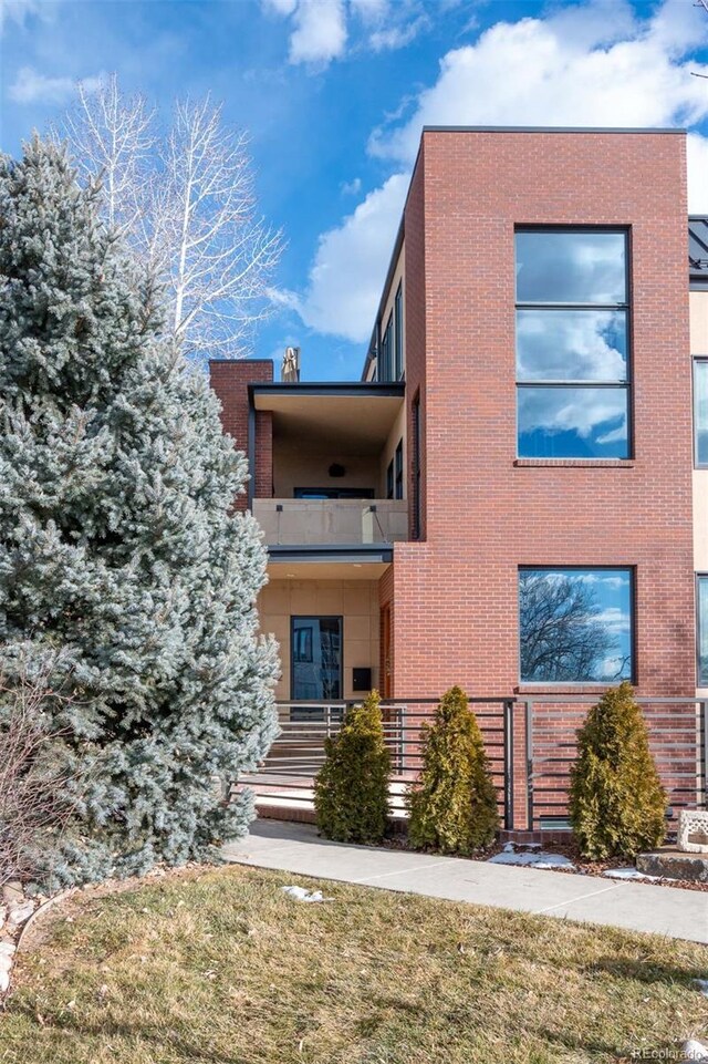 view of front of property featuring a balcony and brick siding