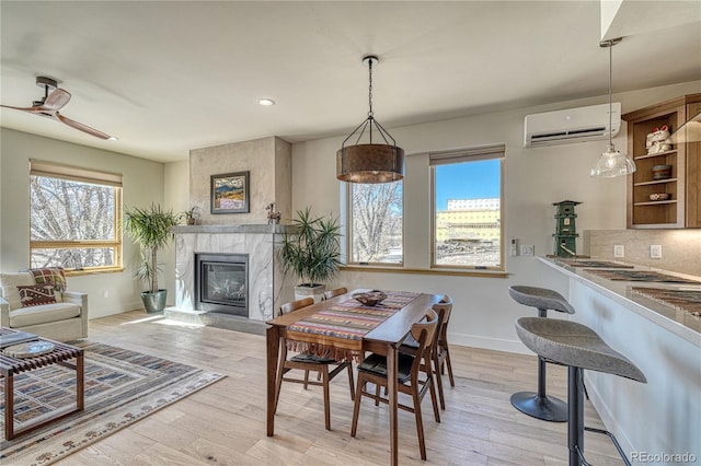 dining room featuring a fireplace, baseboards, a wall mounted air conditioner, recessed lighting, and light wood finished floors
