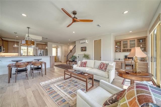 living room featuring recessed lighting, a wall mounted AC, light wood-style flooring, and visible vents