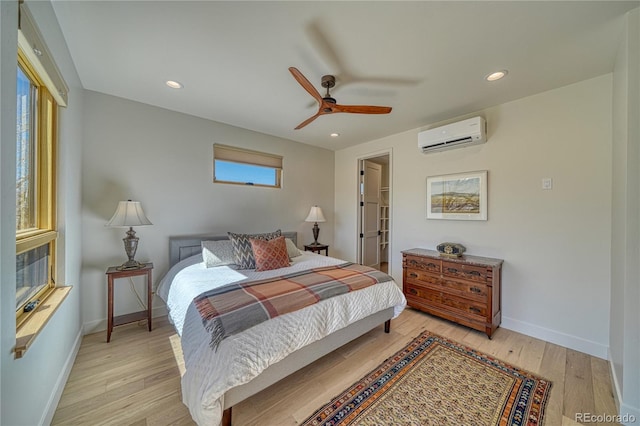 bedroom with a closet, baseboards, light wood finished floors, and a wall mounted air conditioner