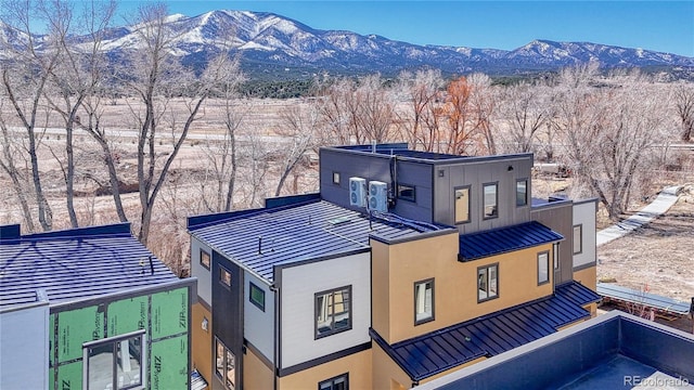 back of property featuring a standing seam roof, a mountain view, stucco siding, and metal roof