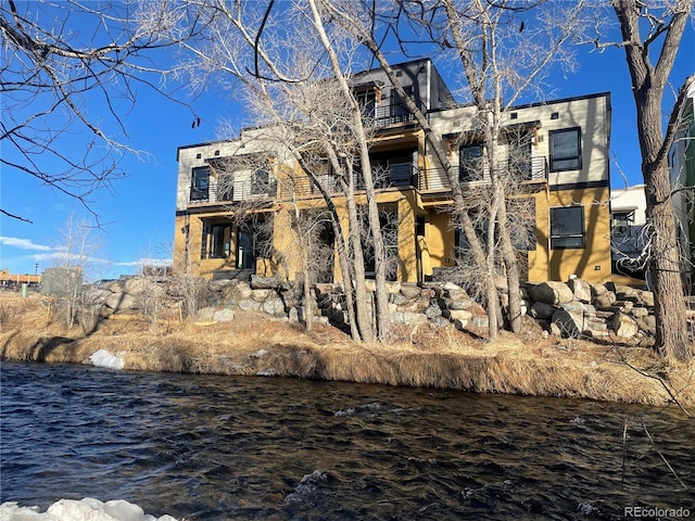back of property with a water view and a balcony