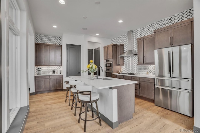21345 E 59th Dr, Aurora, CO 80019 - kitchen with stainless steel appliances, wall chimney exhaust hood, decorative backsplash, recessed lighting, and light wood-style flooring