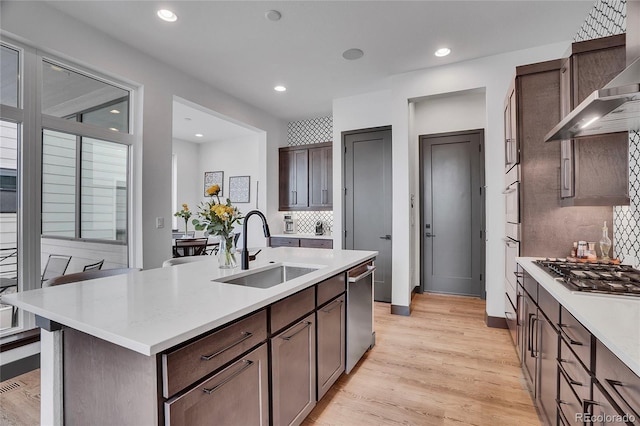 21345 E 59th Dr, Aurora, CO 80019 - kitchen with wall chimney exhaust hood, appliances with stainless steel finishes, light countertops, light wood finished floors, and decorative backsplash