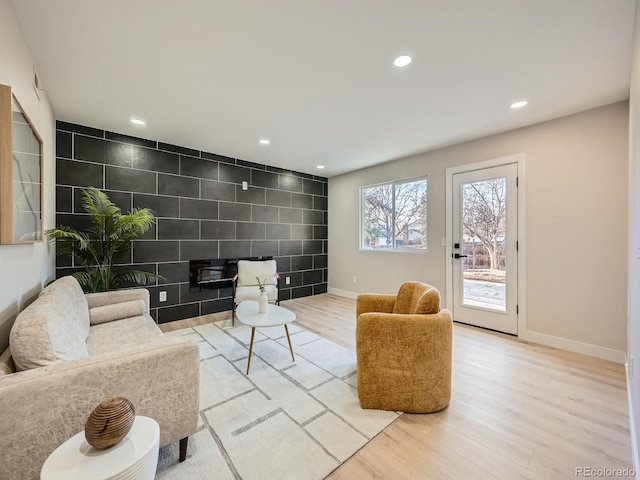 living area featuring an accent wall, baseboards, wood finished floors, and recessed lighting