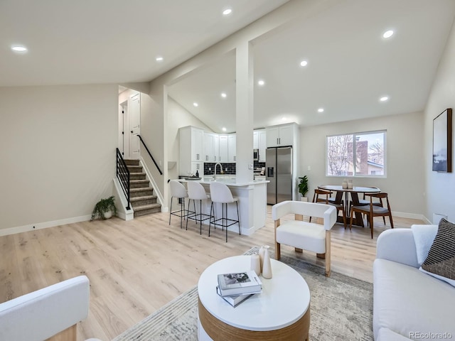 living room with lofted ceiling, stairway, light wood-style flooring, and recessed lighting