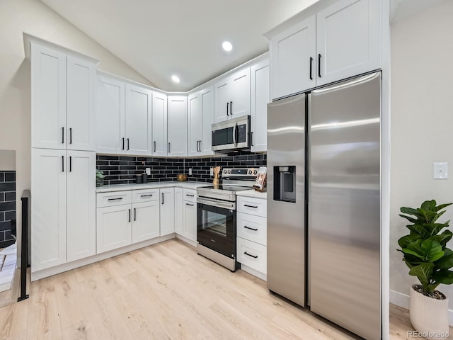 kitchen with stainless steel appliances, lofted ceiling, light countertops, decorative backsplash, and light wood-type flooring