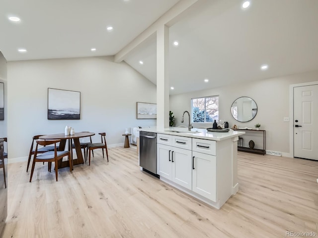 kitchen featuring light wood finished floors, dishwasher, vaulted ceiling with beams, light countertops, and a sink