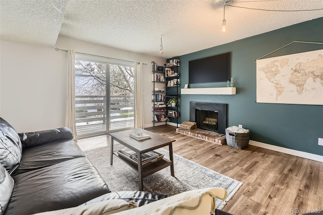3141 S Tamarac Dr Unit 202E, Denver, CO 80231 - living room featuring baseboards, a textured ceiling, a glass covered fireplace, and wood finished floors