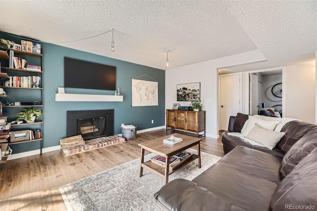 3141 S Tamarac Dr Unit 202E, Denver, CO 80231 - living area featuring wood finished floors, a fireplace, baseboards, a textured ceiling, and rail lighting