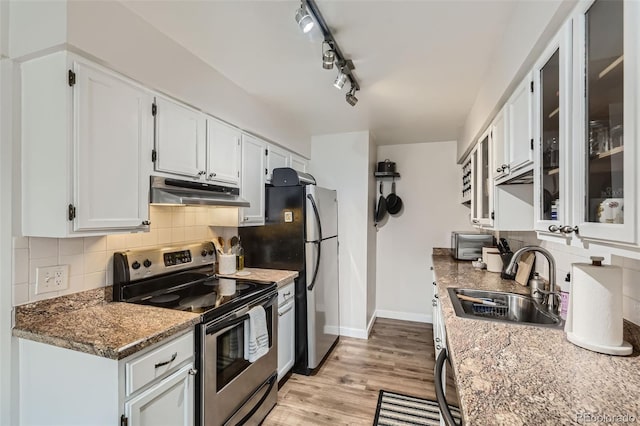 3141 S Tamarac Dr Unit 202E, Denver, CO 80231 - kitchen featuring a sink, stainless steel appliances, baseboards, tasteful backsplash, and under cabinet range hood