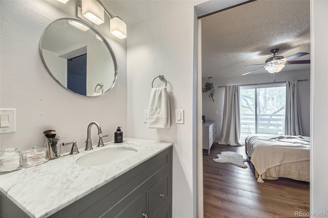 3141 S Tamarac Dr Unit 202E, Denver, CO 80231 - bathroom featuring connected bathroom, vanity, a textured ceiling, a ceiling fan, and wood finished floors