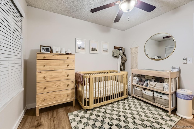 3141 S Tamarac Dr Unit 202E, Denver, CO 80231 - bedroom with ceiling fan, a textured ceiling, a nursery area, wood finished floors, and baseboards