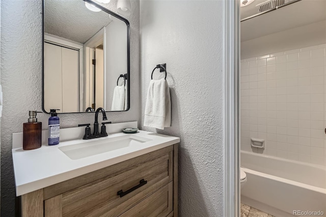 3141 S Tamarac Dr Unit 202E, Denver, CO 80231 - full bathroom with vanity, a textured wall, washtub / shower combination, and toilet