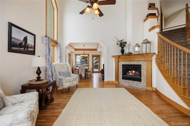 sitting room featuring hardwood / wood-style flooring, a premium fireplace, ornamental molding, and ceiling fan with notable chandelier